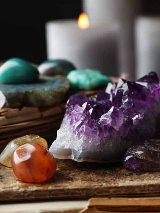 Many different gemstones and blurred candles on background