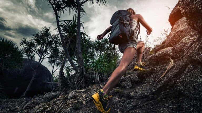 woman hiking on a rocky trail with a large backpack on