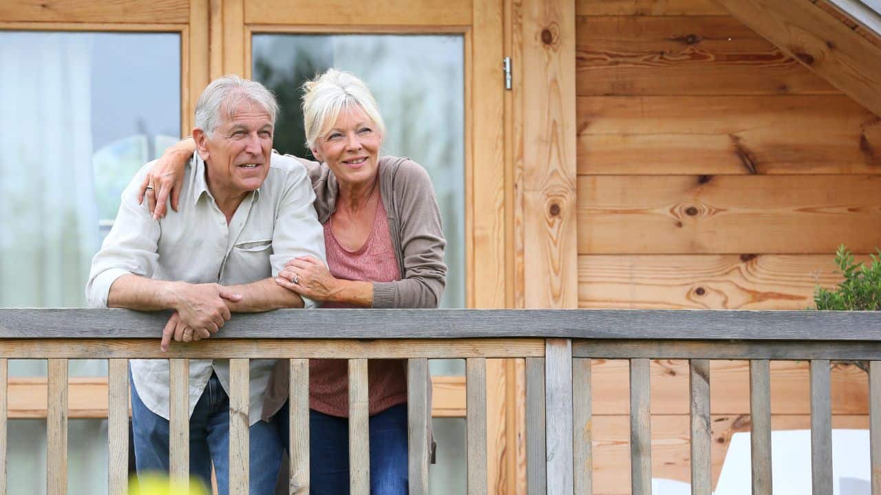 Older couple standing outside log cabin