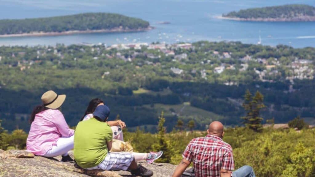 People sitting at the top of a hike enjoying the view of Bar Harbor