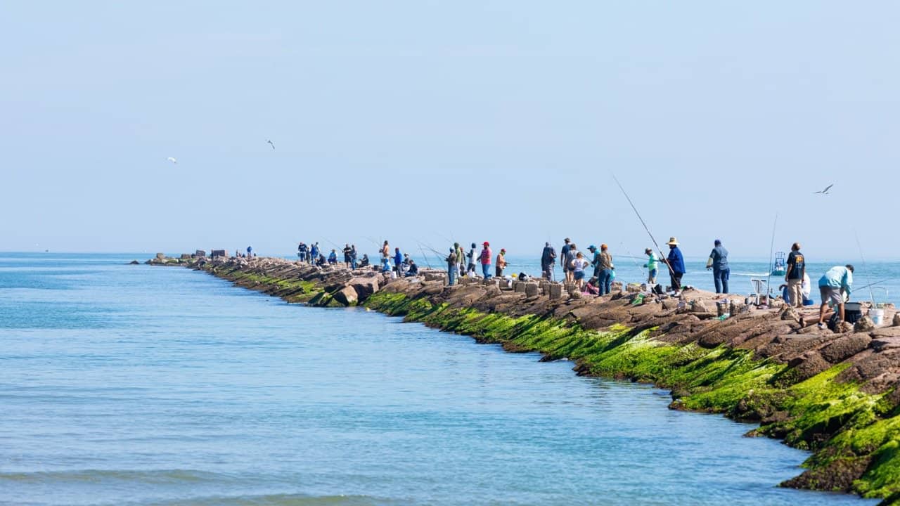 South Padre Island, Texas, USA - November 19, 2019: People fishing on a breakwater at the Brazos Santiago Pass