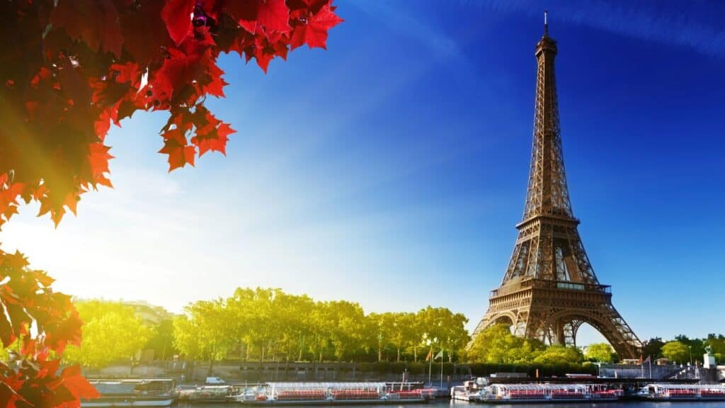 Autumn in Paris at the Eiffel Tower with river cruise boats lined up on the Seine.