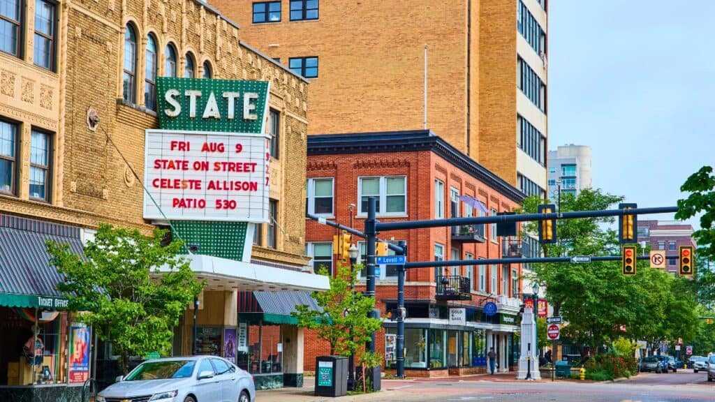 Vibrant downtown Kalamazoo street scene featuring the historic State Theatre marquee advertising Celeste Allison. A blend of classic and modern architecture with bustling street life and community