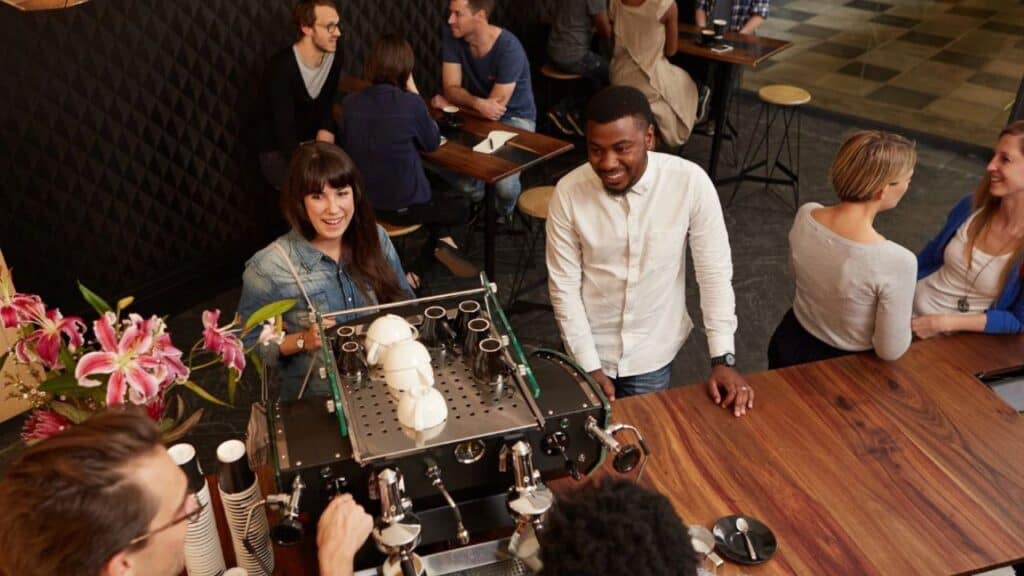 Couple laughing with baristas at cafe