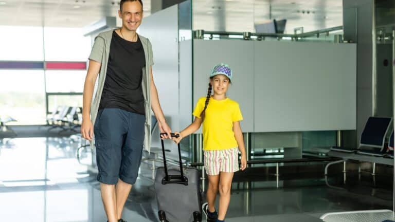 Father and daughter coming through security with their suitcases.
