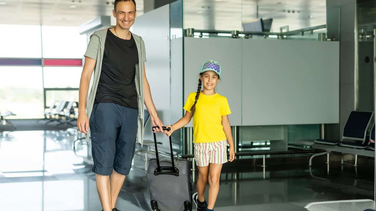 Father and daughter coming through security with their suitcases.