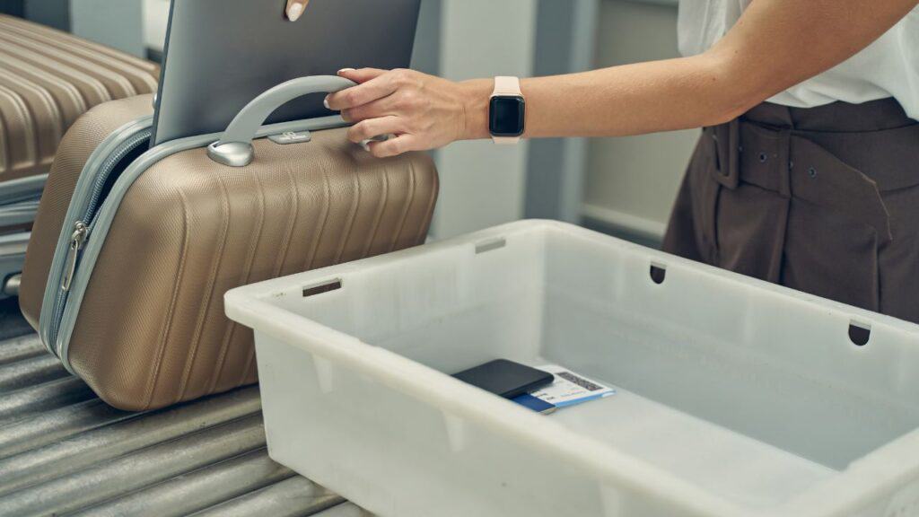 Carry on bag and security bin going through airport security scan.