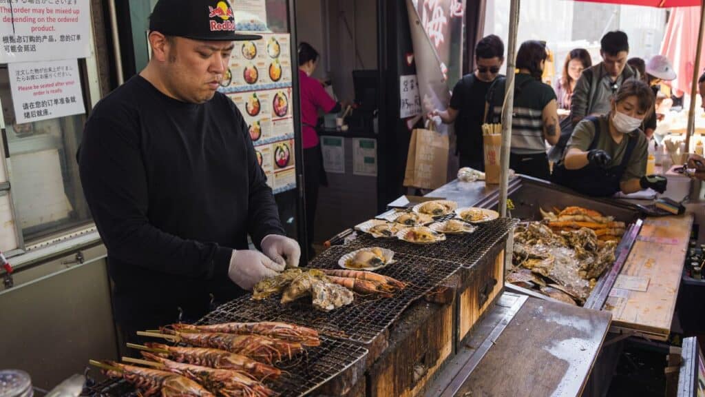 Tokyo, Japan - April 12, 2023: street food stall on Tsukiji Fish Market with unidentified people. It is a major tourist attraction. Before 2018, it was the largest wholesale fish market in the world