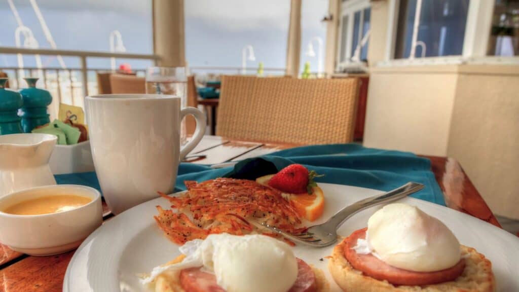 Poached eggs, Canadian bacon, bearnaise sauce, and hash browns for breakfast overlooking the ocean.