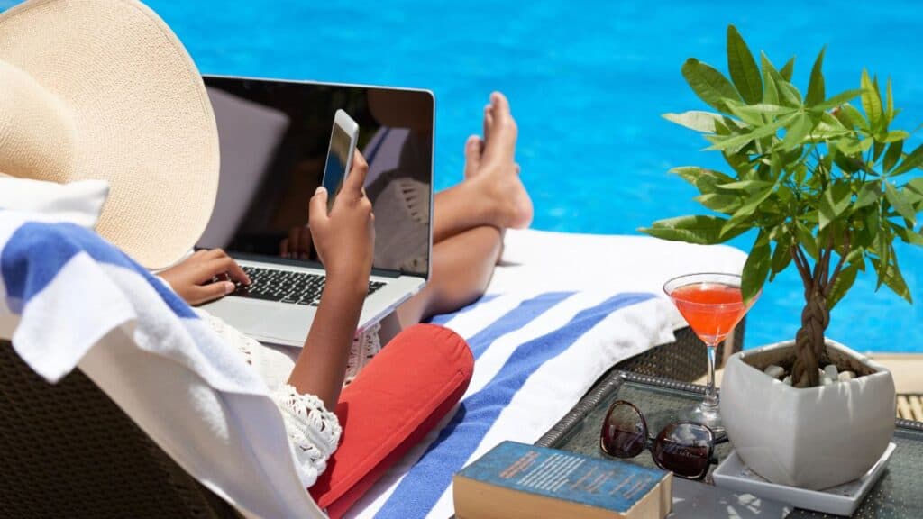 Woman at the pool working on her phone and laptop