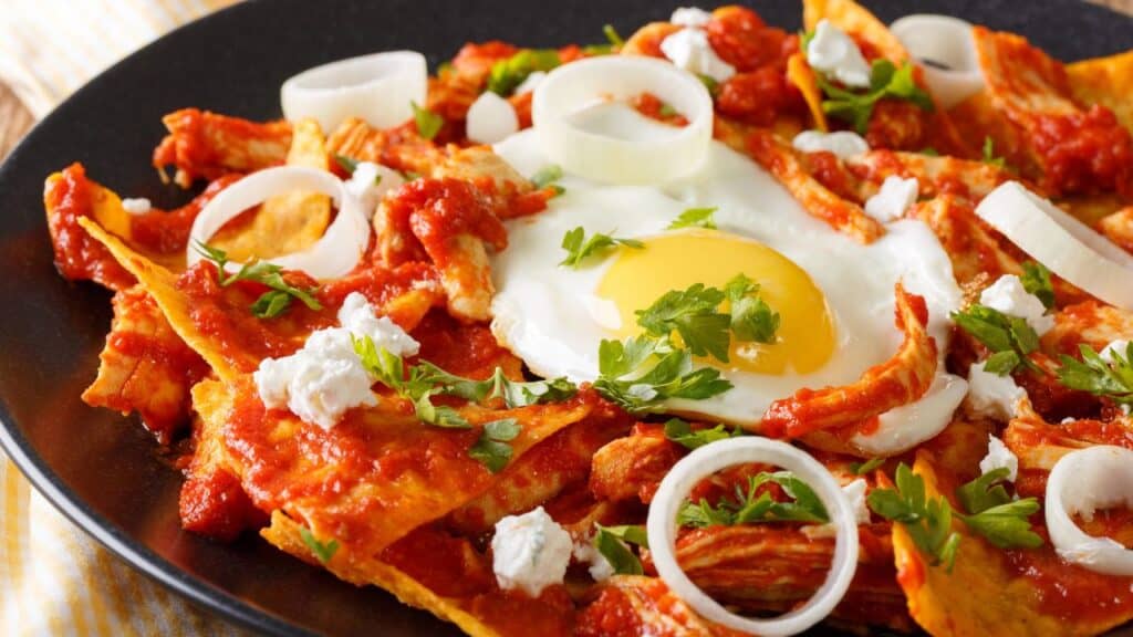 Tortillas with tomato salsa, chicken and egg close-up.