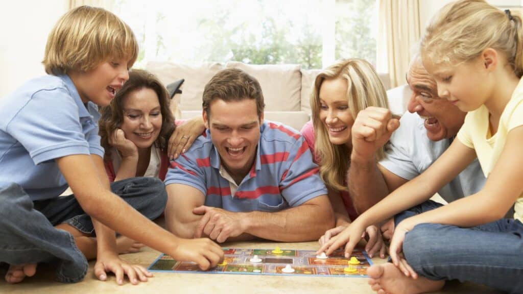 Family Playing Board Game At Home With Grandparents Watching