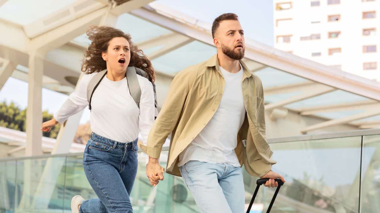 Young couple racing through the airport trying to not miss their flight