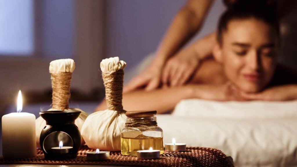 Woman relaxing in spa salon with herbal bags on wooden tray