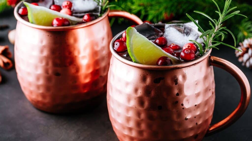 Moscow Mule cocktail with cranberries and lime in copper mugs for Christmas