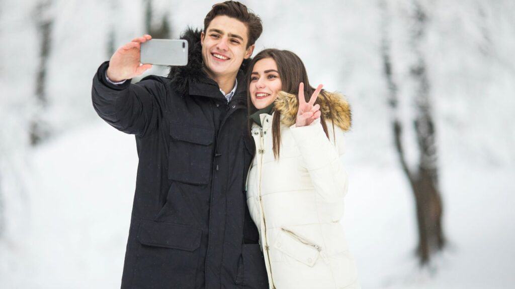 Young couple posing out in the snow for a selfie.