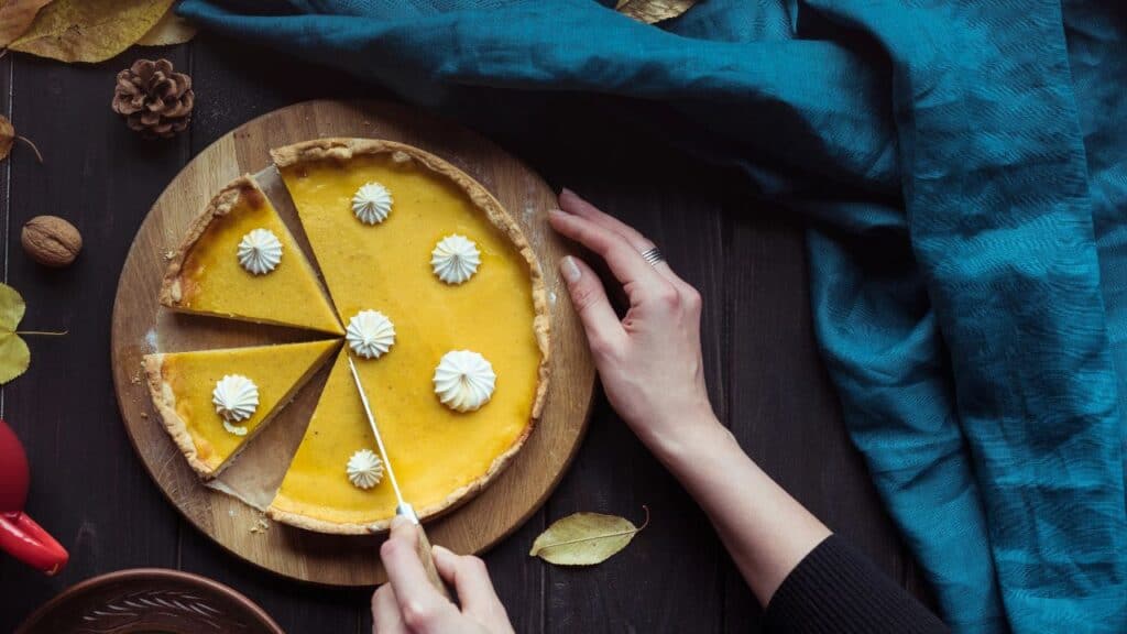 Overhead view of a pumpkin pie being cut into slices