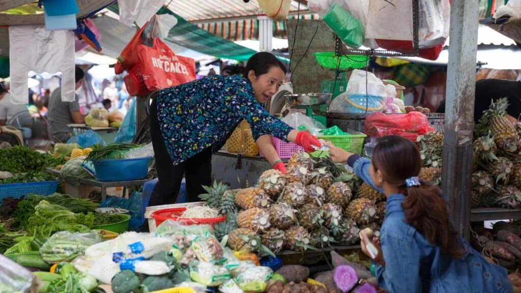 Vietnamese woman is selling fruits and vegetables at the wet market
