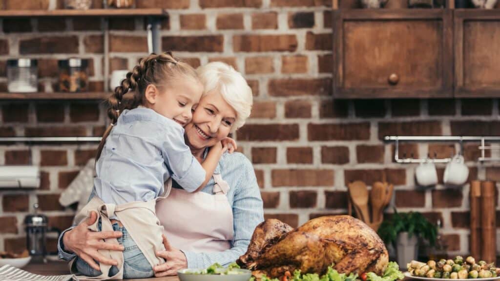 Grandmother and granddaughter in kitchen with turkey dinner on the counter