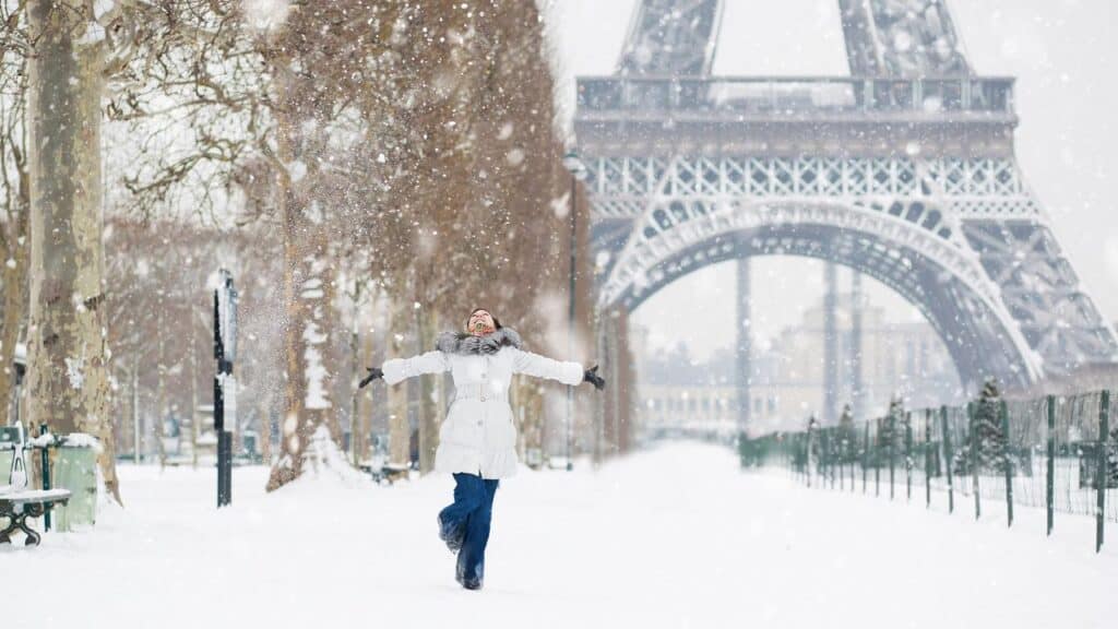 Woman spinning in the snow in front of the Eiffel Tower in Paris, France