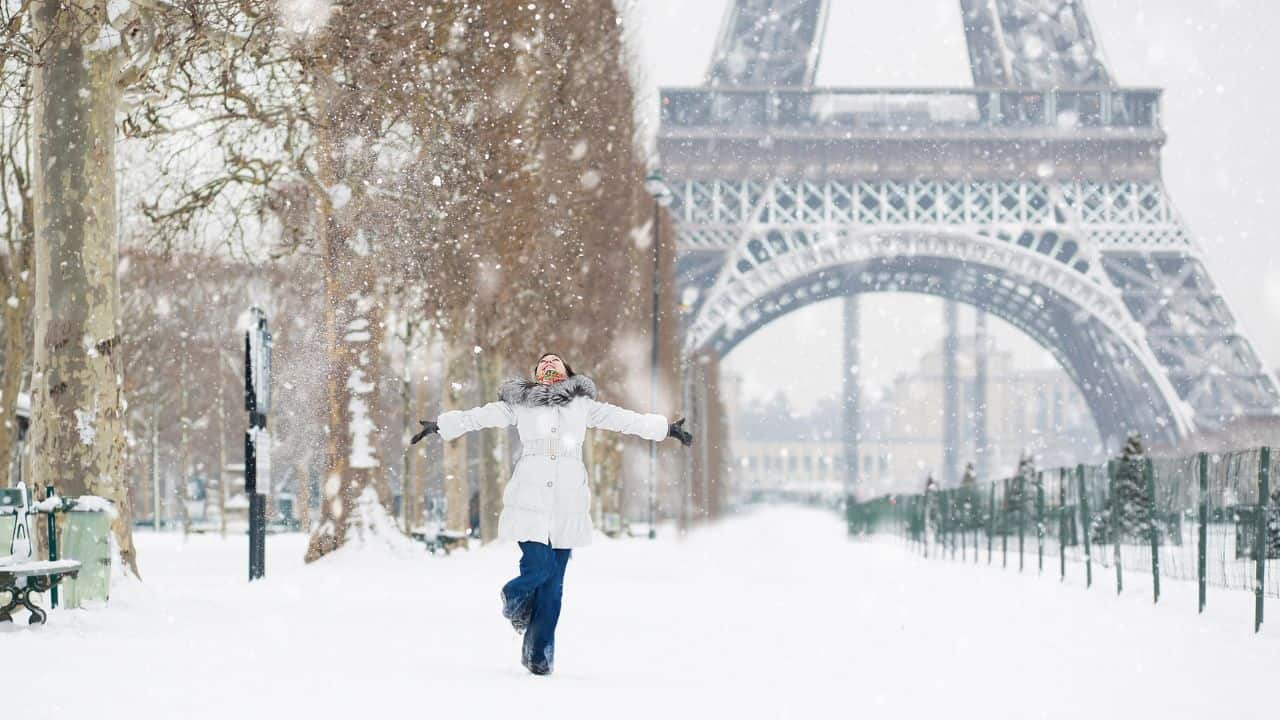 Woman spinning in the snow in front of the Eiffel Tower in Paris, France