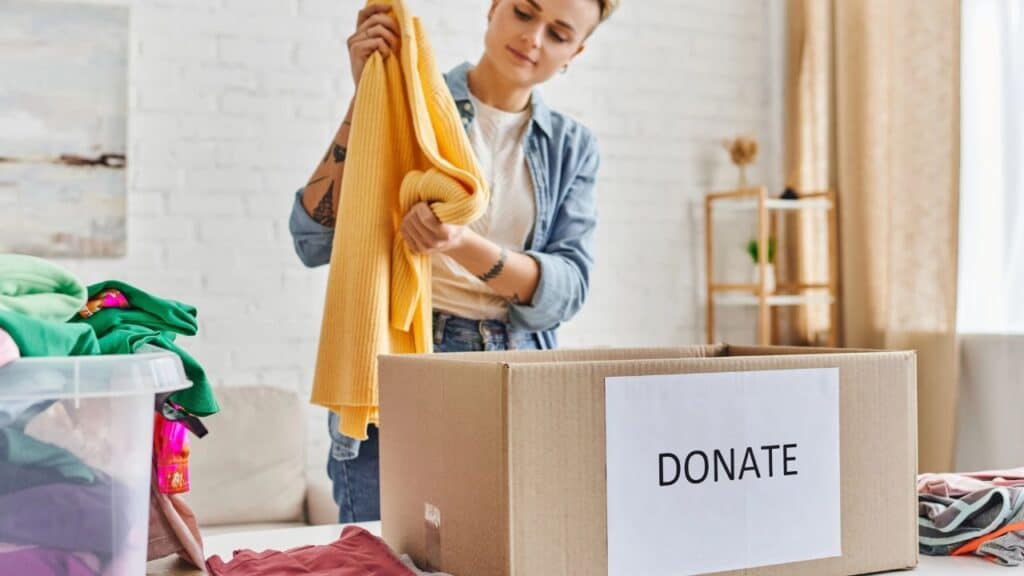Young woman putting a sweater in a donation box for charity.