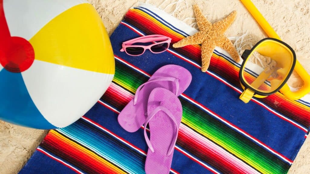 Beach blanket with a snorkel, beach ball, flip flops, sunglasses and a starfish on it.