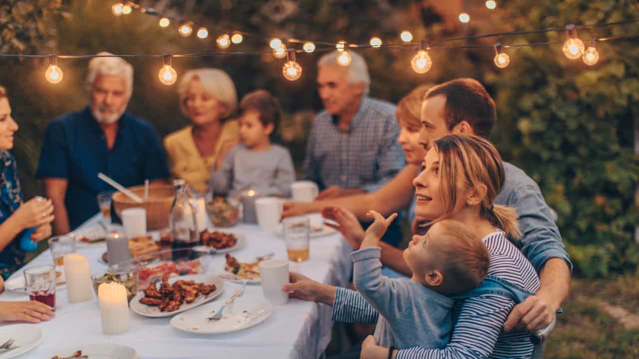 Multi-generational family around a table outside in the backyard.